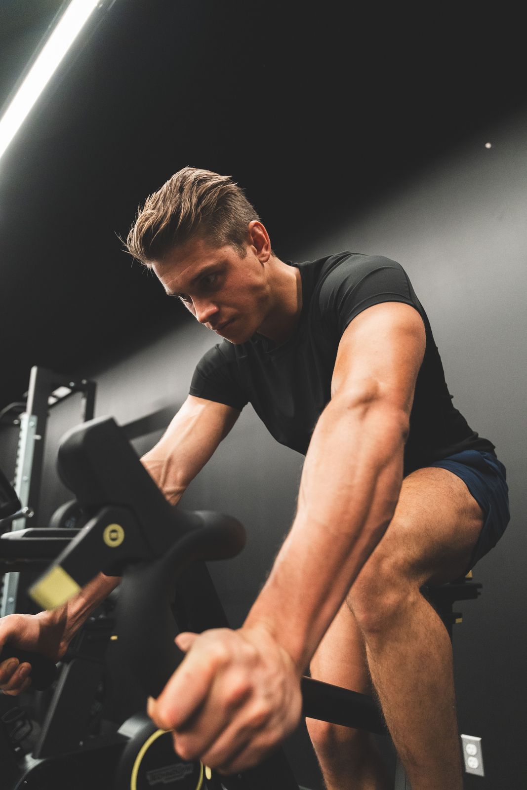 Focused athlete pushing the handles of an air bike during a conditioning effort
