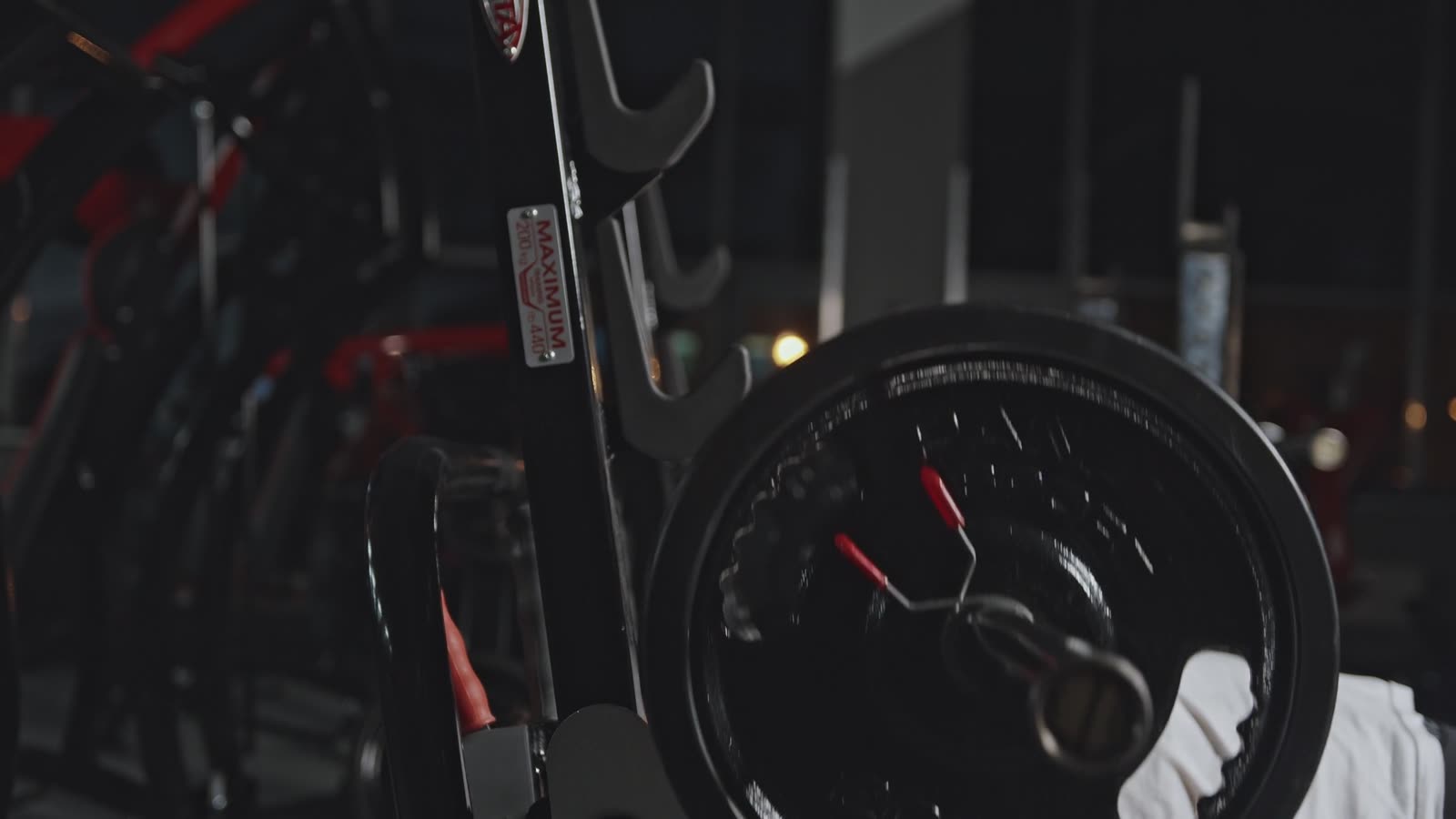 Lifter pressing a loaded barbell on a bench in a dimly lit gym