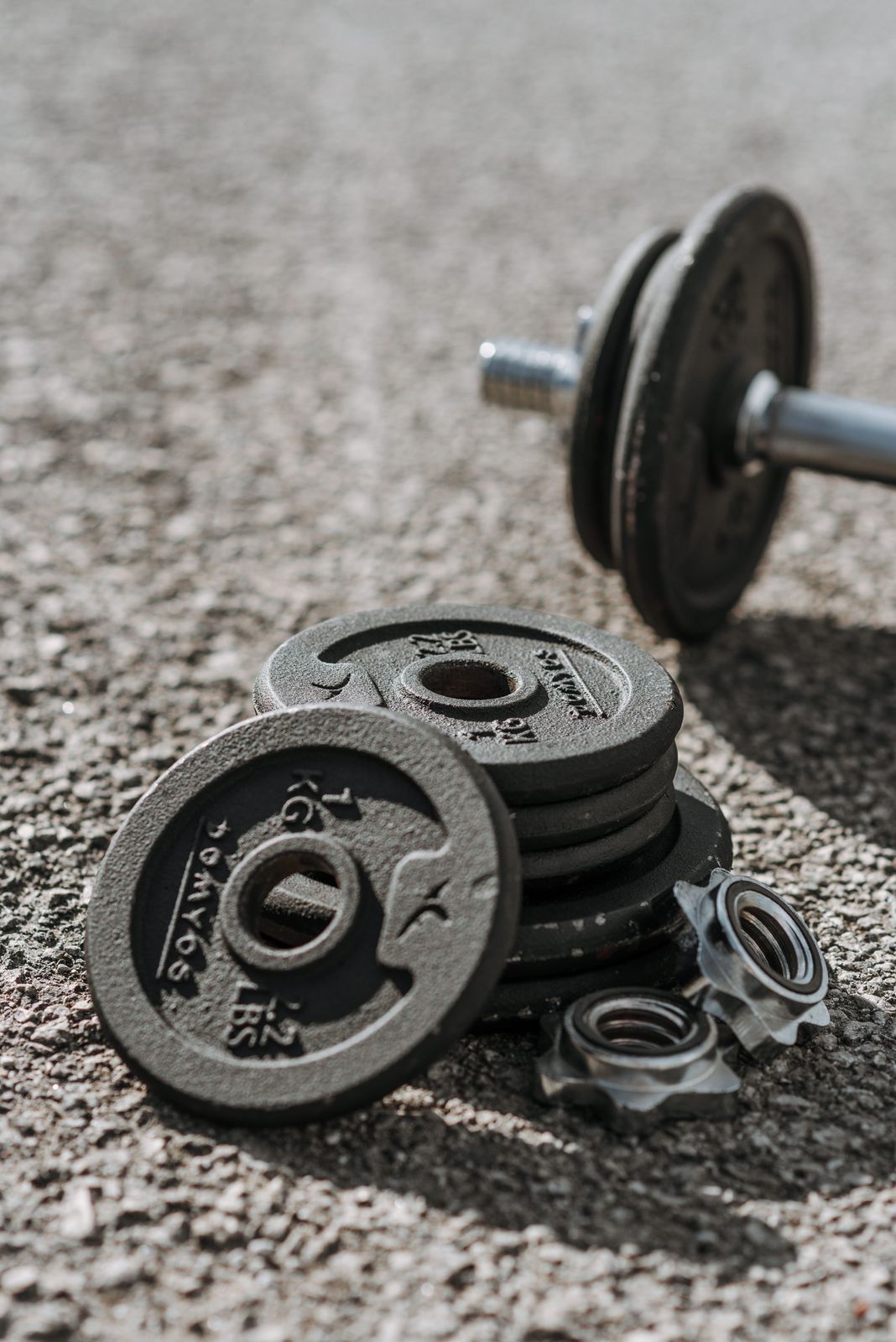 Stack of cast iron weight plates and spin-lock collars beside a dumbbell handle